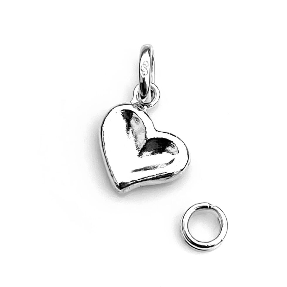 Thumb Print Heart Charm resting on velvet, angled for display.