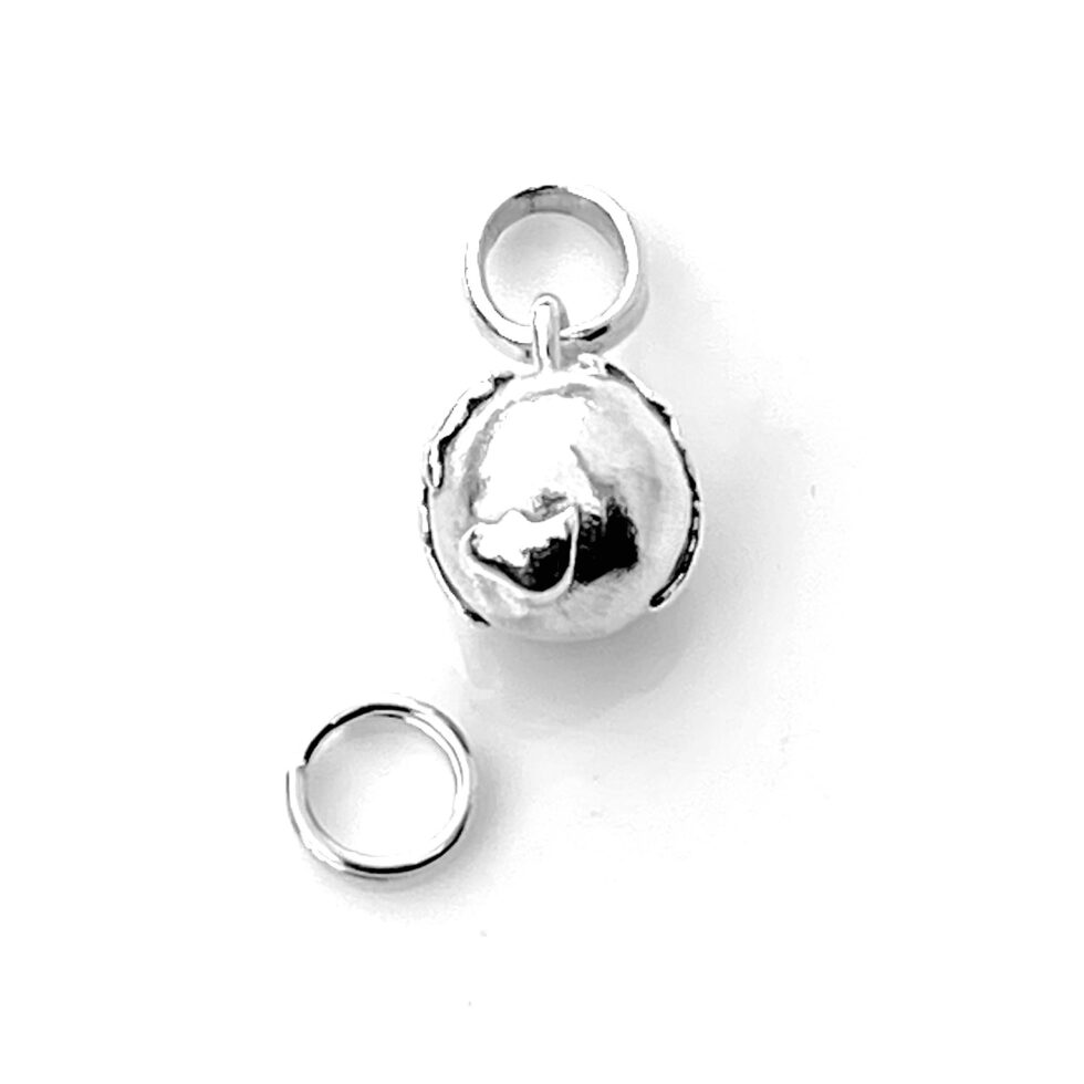 Globe charm photographed in natural light to highlight its polished finish.