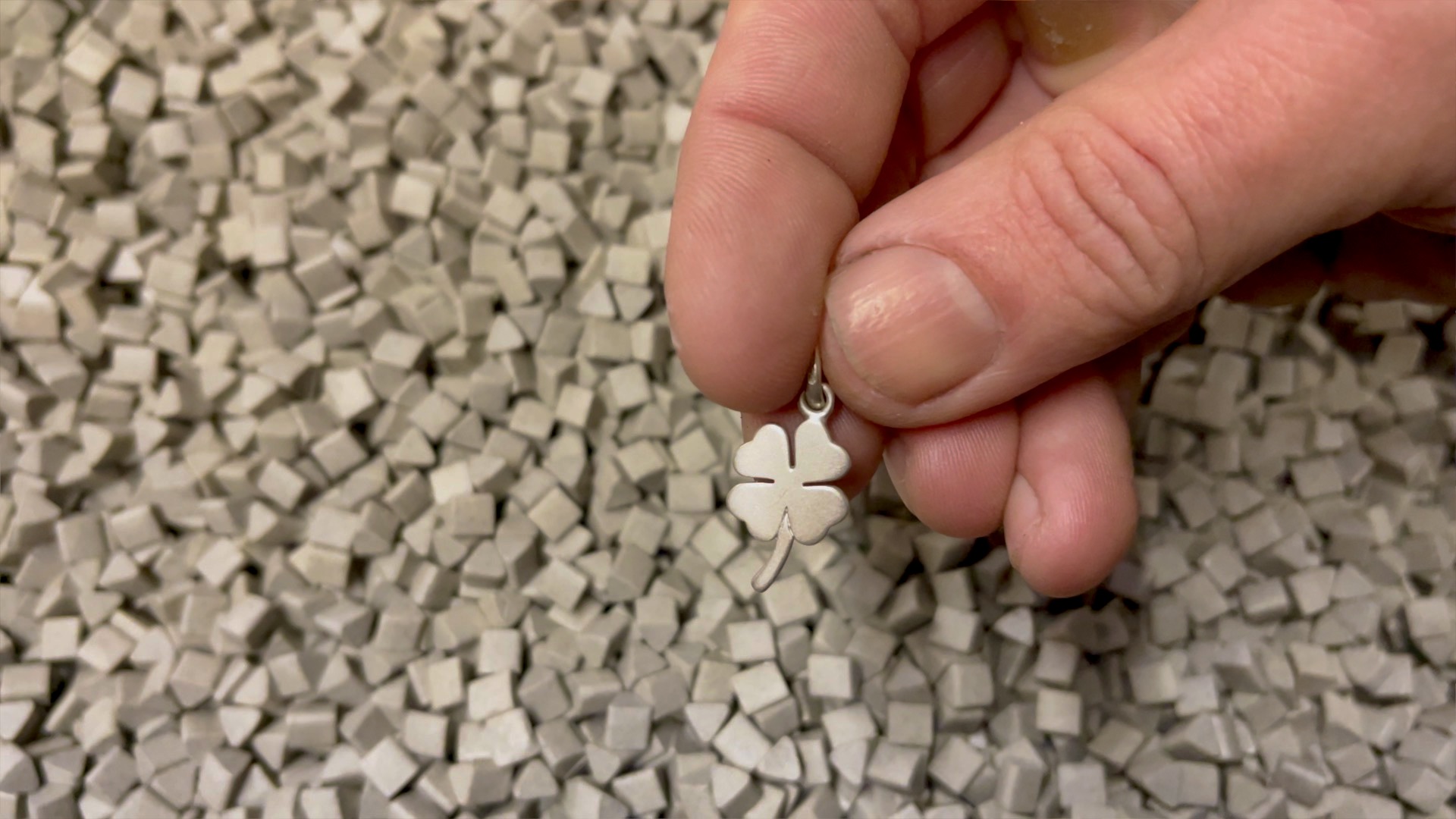 Four leaf clover charm emerging from the ceramic media polishing process.