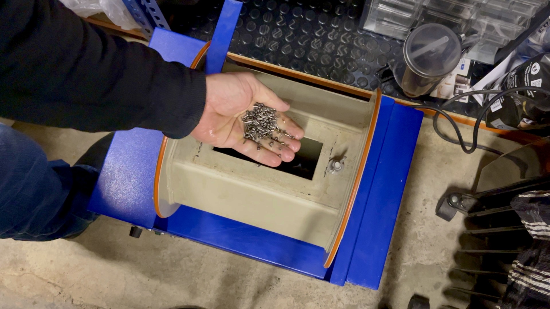 Charm submerged in a stainless steel shot tumbler for burnishing.