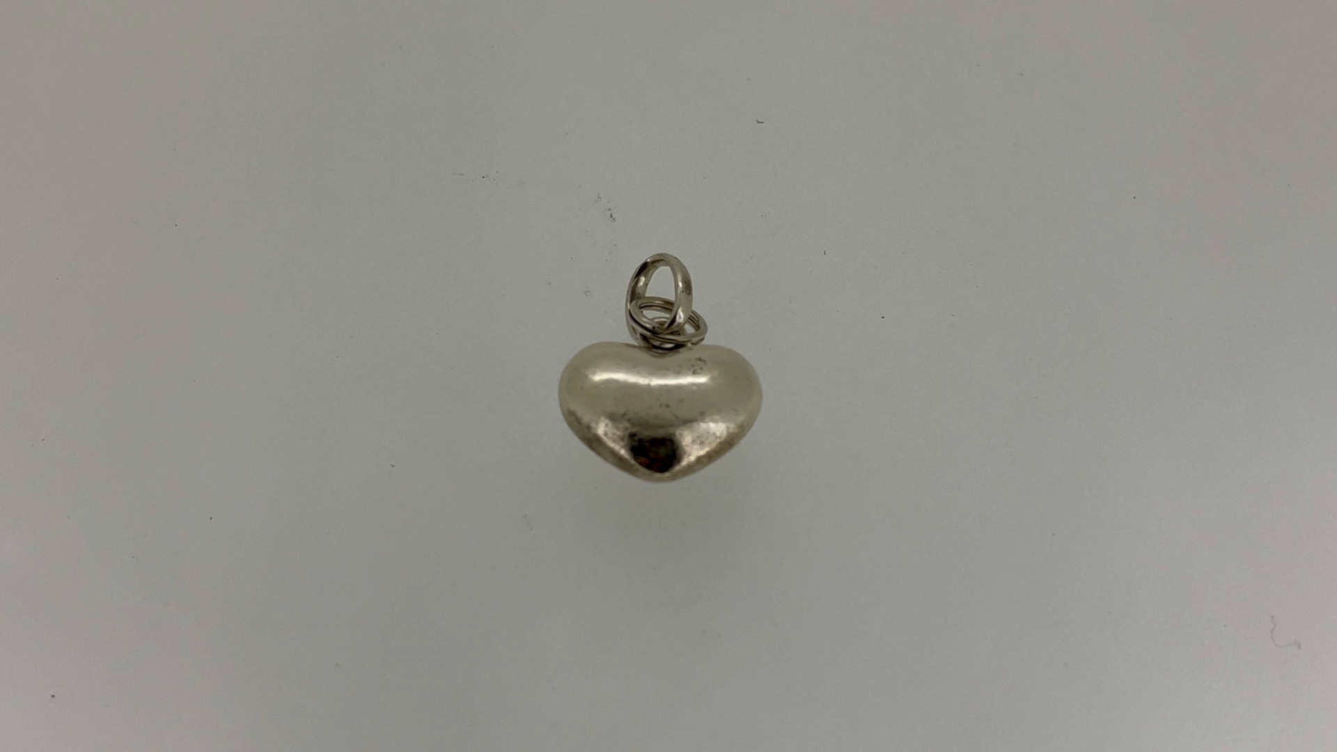 Close-up of a vintage Links of London heart charm before restoration, showing tarnished silver.