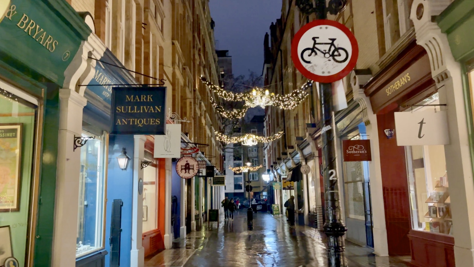 Cecil Court illuminated at night with subtle festive decorations.