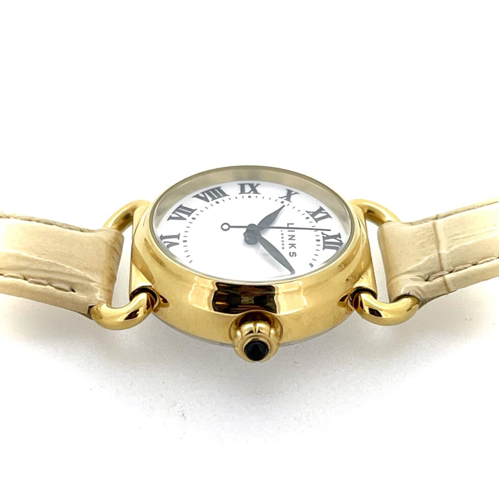 Side profile showing domed mineral glass and polished gold-plated case.