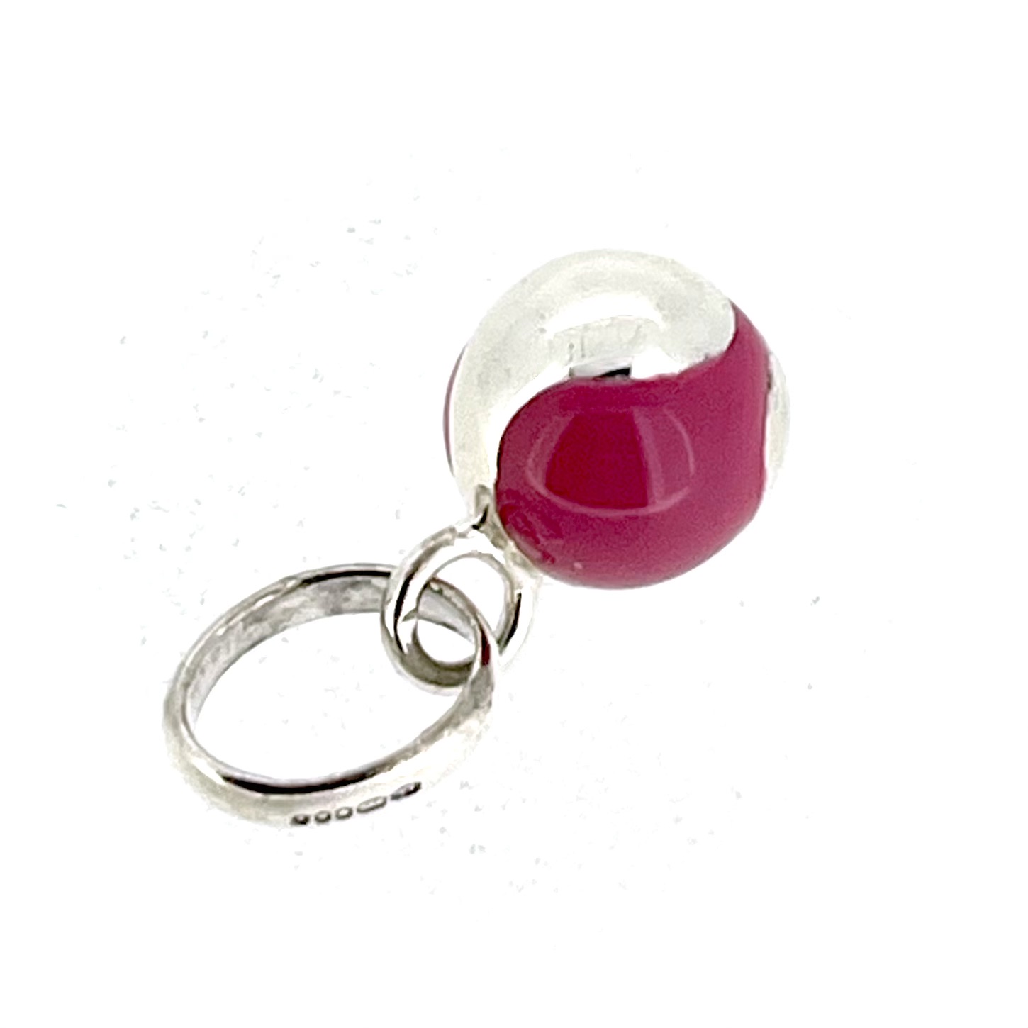 Angled view of vintage pink enamel tennis ball charm with oval bail