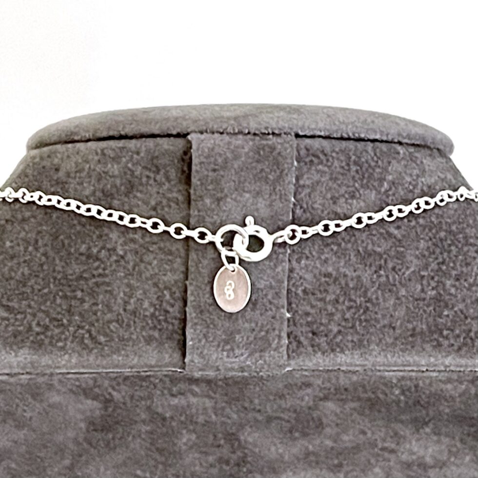 Close-up of sterling silver oval link necklace chain with bolt ring clasp and tag