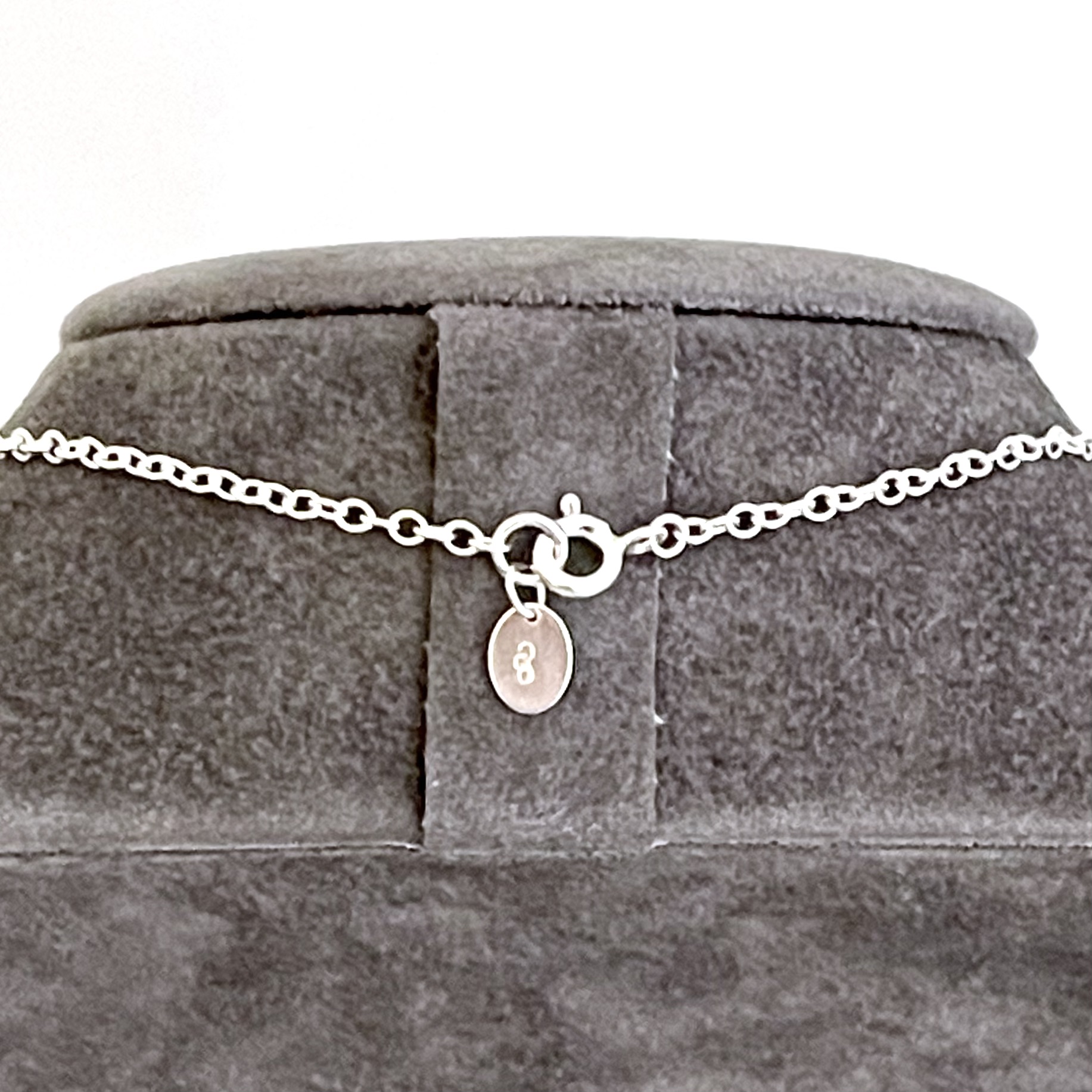 Close-up of sterling silver oval link necklace chain with bolt ring clasp and tag