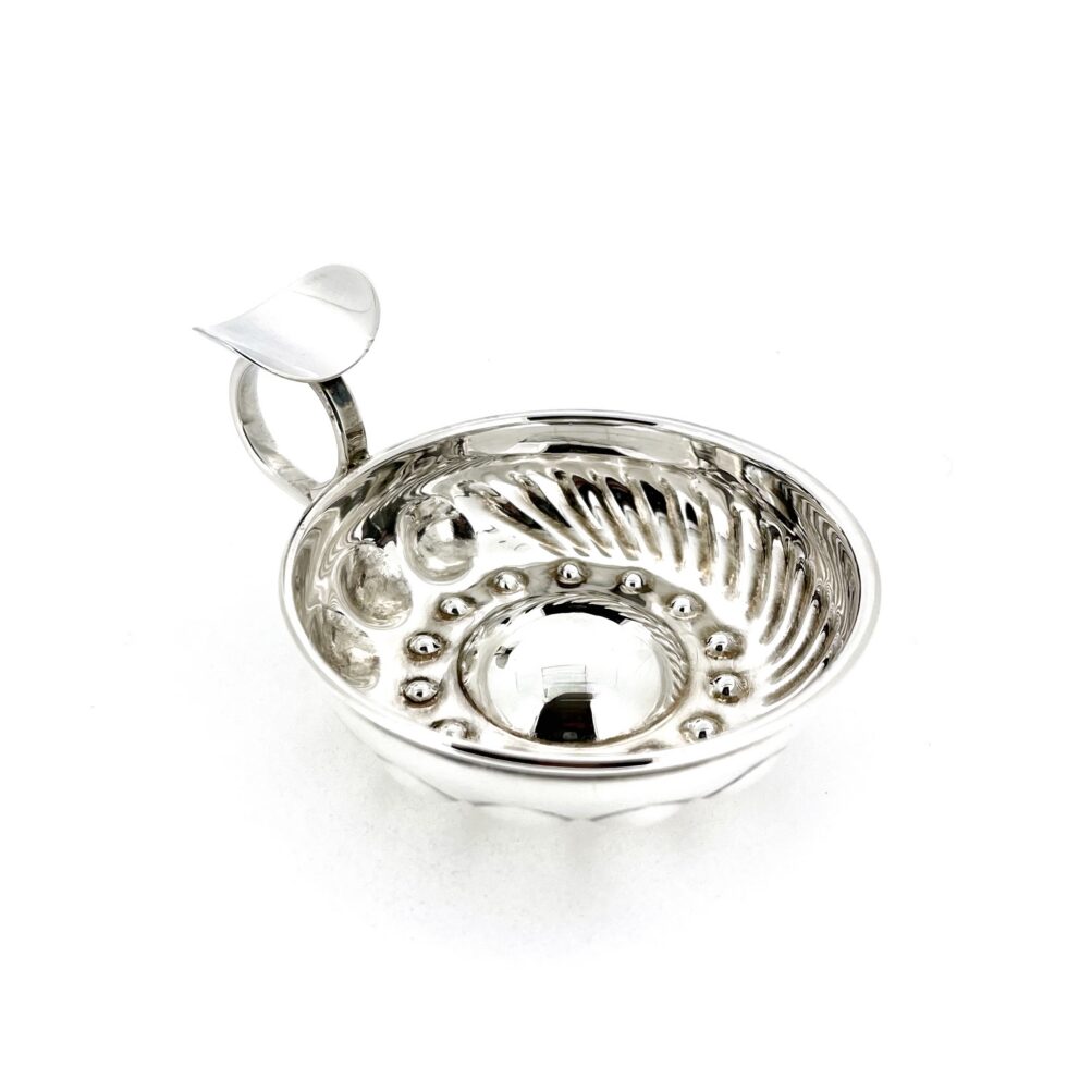 Angled view of sterling silver tastevin with raised central dome and bosses